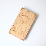 An engraved wooden plaque with a detailed family portrait on a minimalist desk.